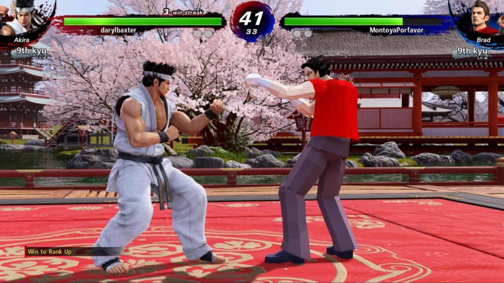 Virtua Fighter 5 REVO のゲームプレイ スクリーンショット。桜を背景にした日本庭園のステージで、アキラとブラッドが対決しています。