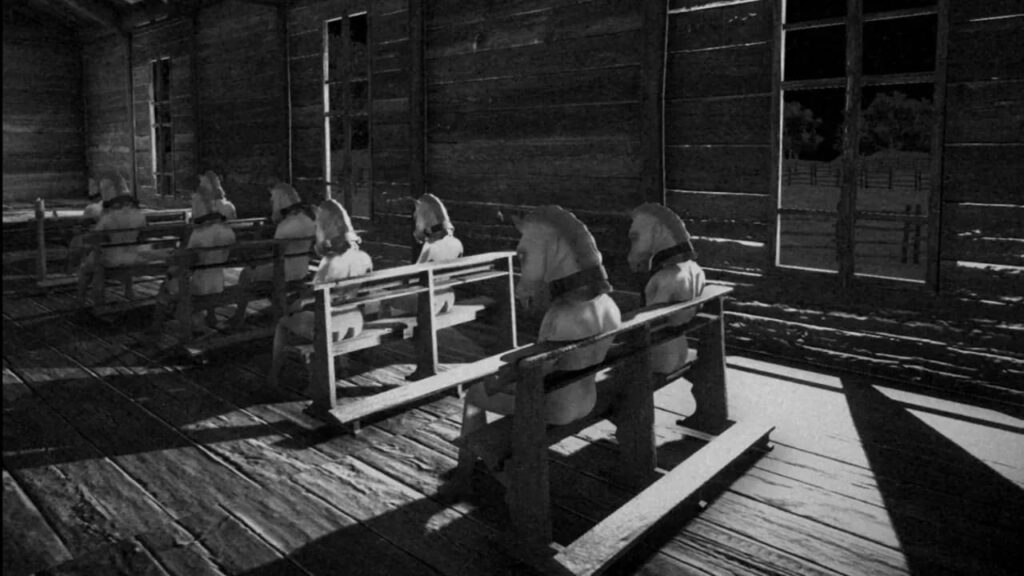 나체의 인물들이 말 가면을 쓴 채 앉아있는 장면