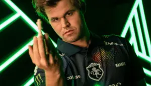 Magnus Carlsen i lagtröja håller upp en vit schackpjäs i Esport World Cup 2025.