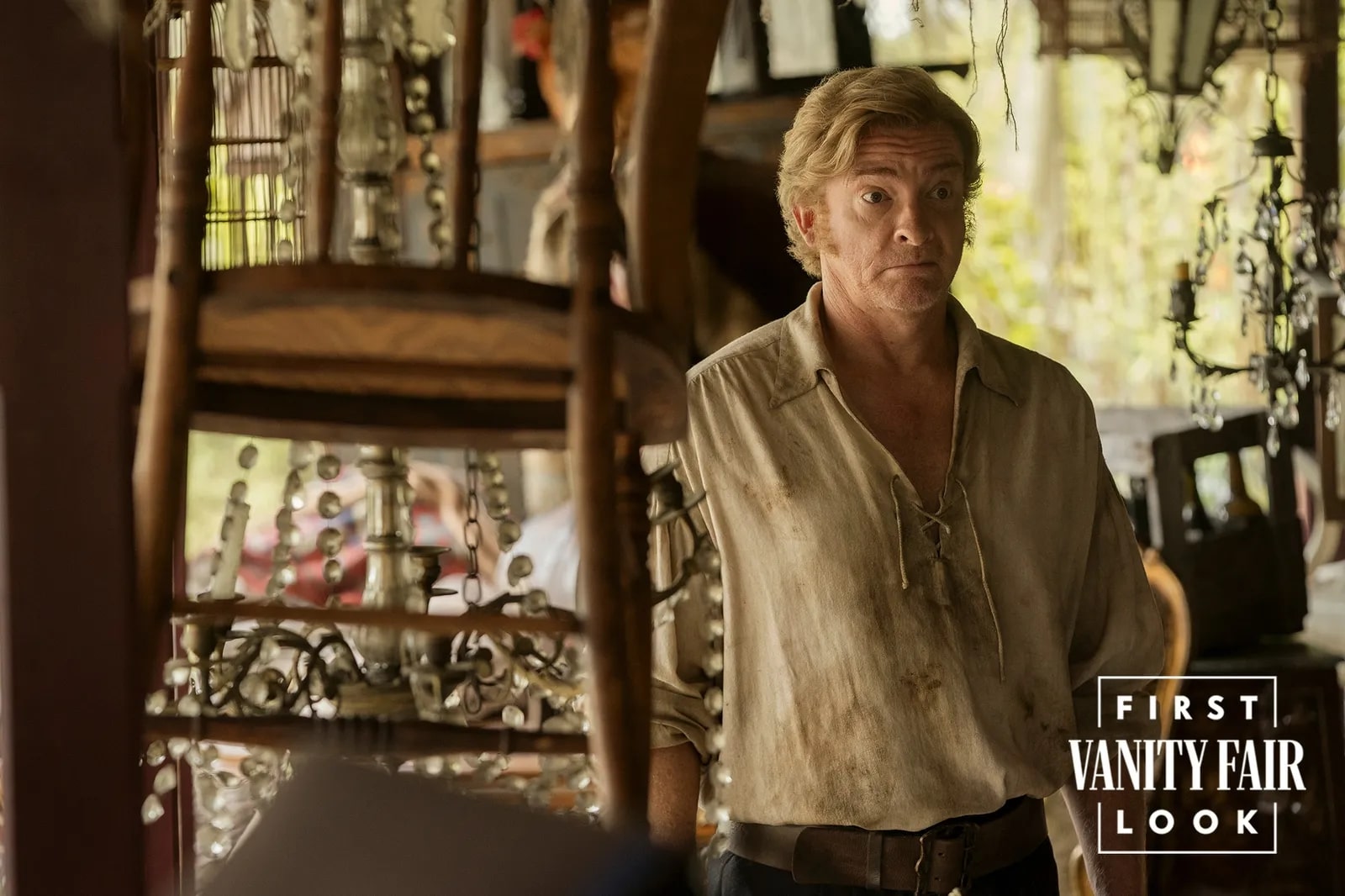 Rhys Darby as Stede Bonnet in Our Flag Means Death Season 2 standing beside a chair. 