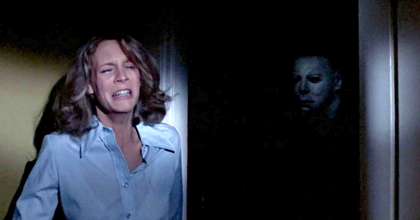 Laurie Strode cries as Michael Myers appears in the darkness  as part of an article about the best horror movies on streaming.