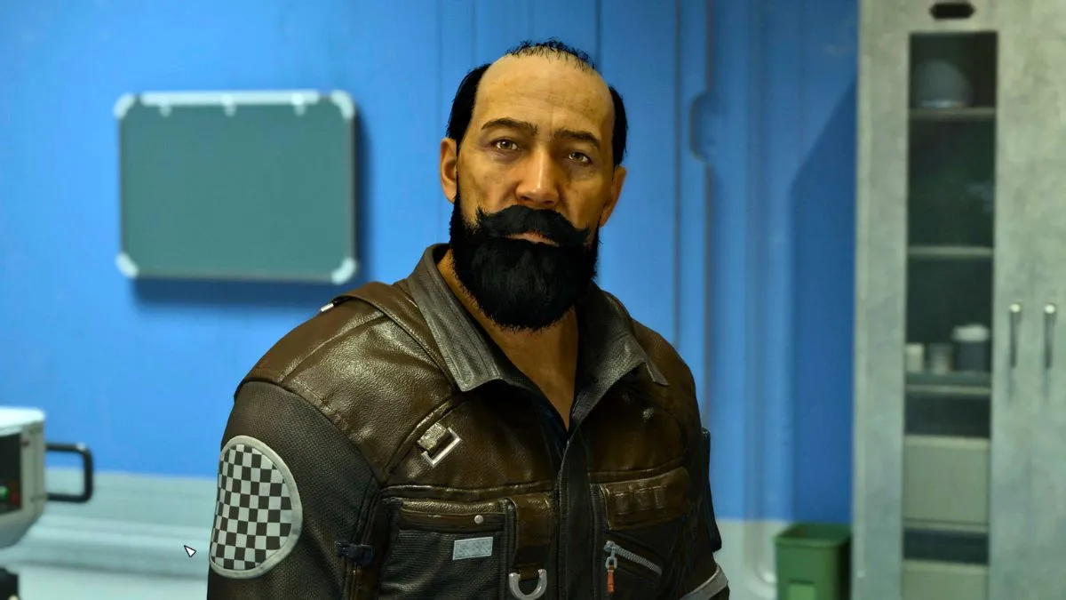 An image of Rafael in Starfield as part of a guide on how to recruit him in the game. The image shows him wearing his jumpsuit and standing in front of a blue wall. He's balding and has a long, well-kempt beard.