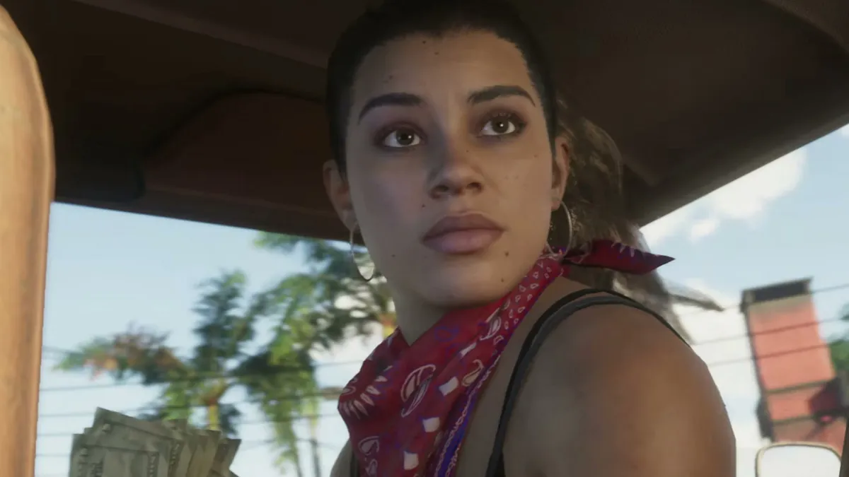 A women in a car, turning around to face the back seat, with a bandana round her neck. This image is part of an article about who voices Lucia in GTA 6.