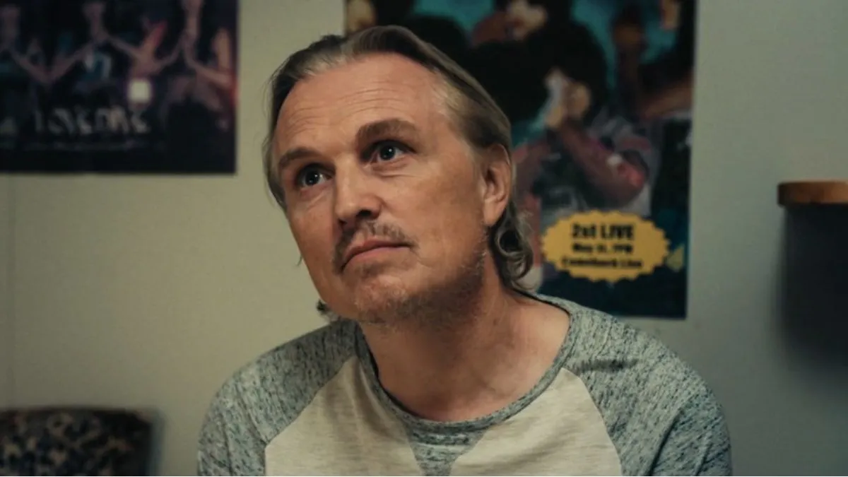 Posters on a wall behind a man in Night Country. This image is part of an article about what is True Detective: Night Country's AI poster controversy. 
