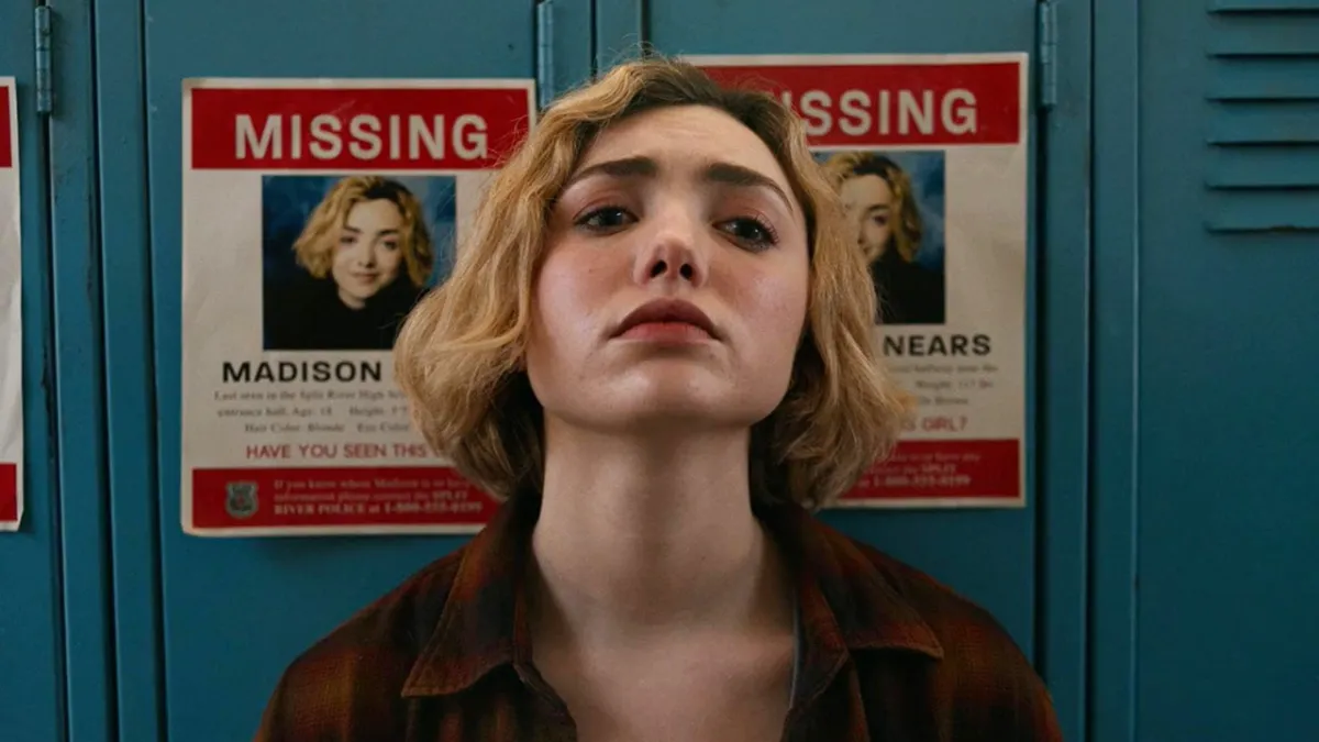 A blonde girl leaning against lockers. The lockers have a picture of her on a missing poster.