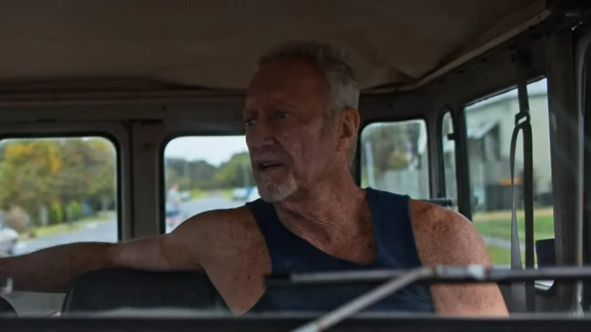 Slim, an older man in a tanktop, driving a truck