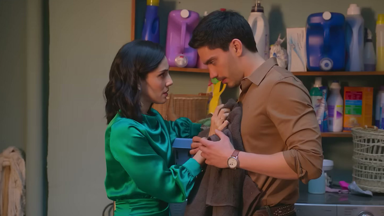 A man and a woman in a laundry room, looking awkwardly/romantically at each other.