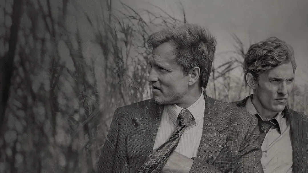 Marty and Rust stand in tall grass. This image is part of an article about all four seasons of True Detective, ranked from worst to best. 