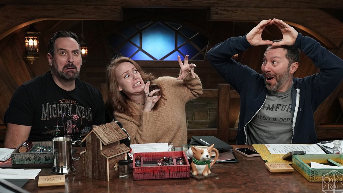 Two men and a woman pull faces at a table in a promo still from Critical Role: Campaign 3, Episode 83.