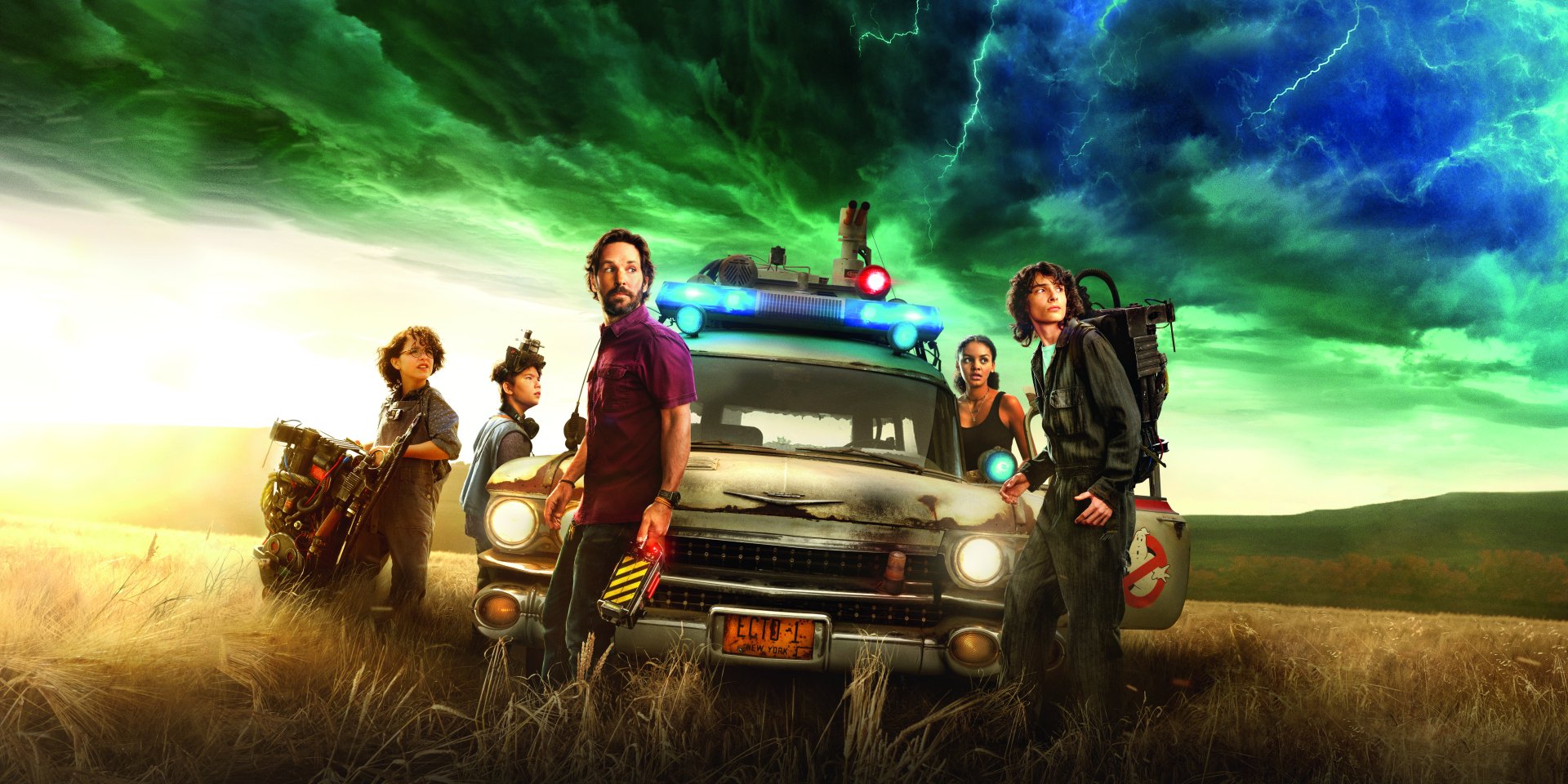 Paul Rudd, Mckenna Grace, and Finn Wolfhard stand next to Ecto-1 in Ghostbusters: Afterlife.