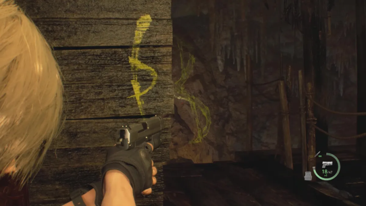 Leon aims his pistol at yellow graffiti. This image is part of an article about how to solve the cave puzzles in Resident Evil 4 remake.