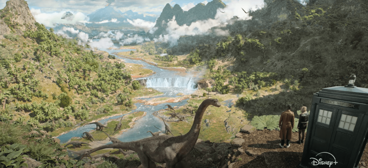 The Doctor and Ruby stand on a cliff looking at some dinosaurs in Doctor Who.