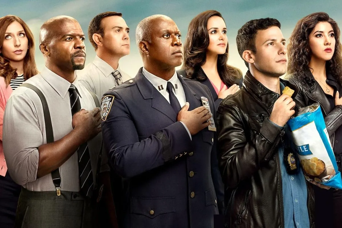 The cast of Brooklyn Nine-Nine with their hands held against their chests.