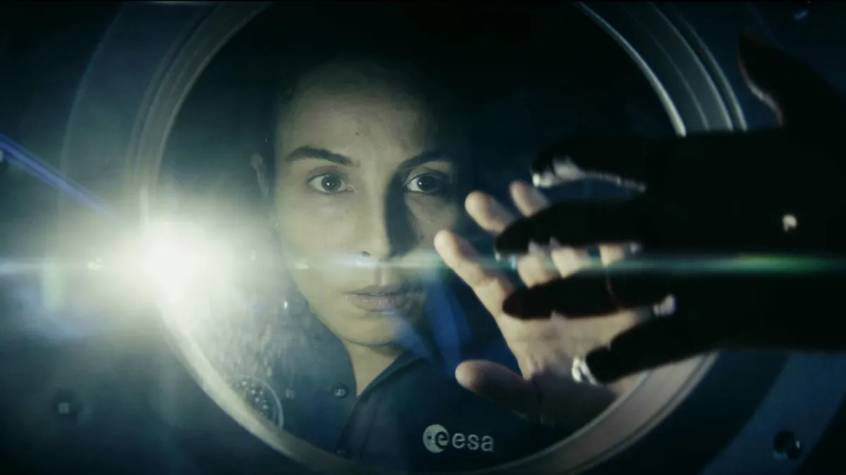Jo in the series Constellation, a woman peering through a glass window on the International Space Station