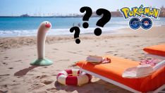 Photo of a beach scene with the Pokemon Wiglett popping out of the sand, with several question marks nearby