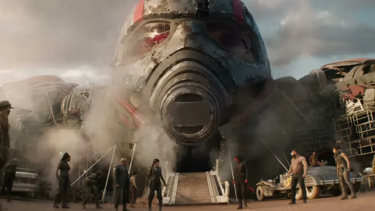 Ant-Man's giant corpse, with several other characters standing around in front of it. 