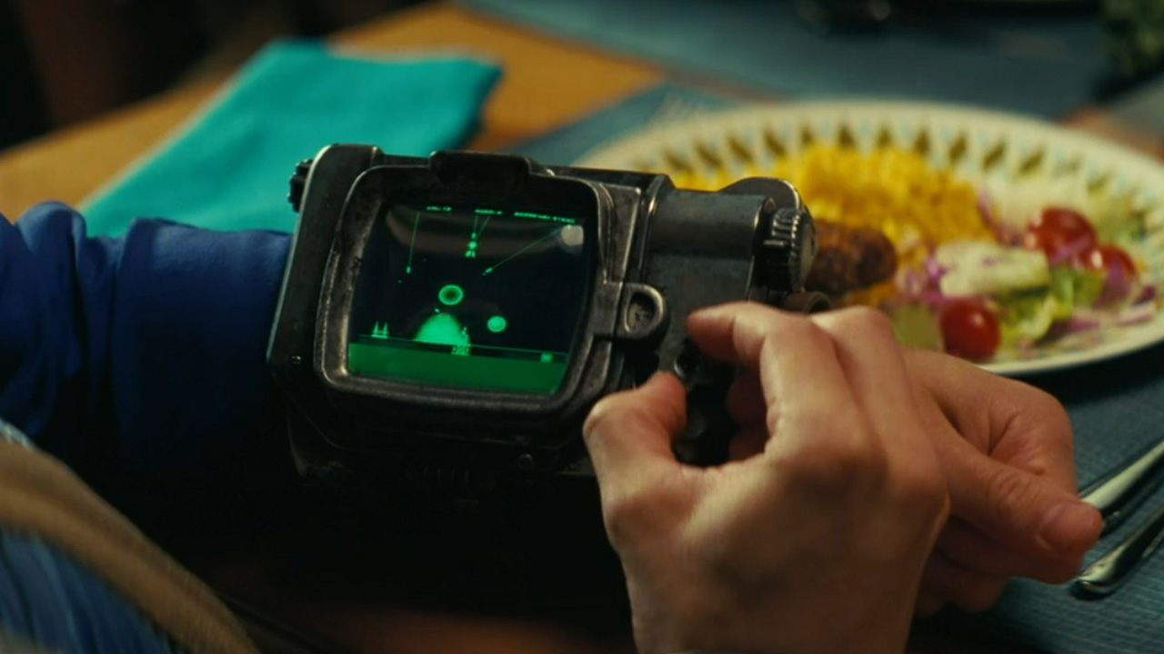 A person playing a Missile Command-style game on a wrist computer.