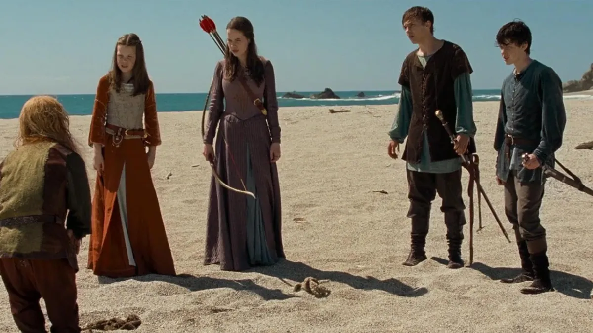 The four Pevensie children in Prince Caspian, standing on a beach, with weapons in their hnand.s 