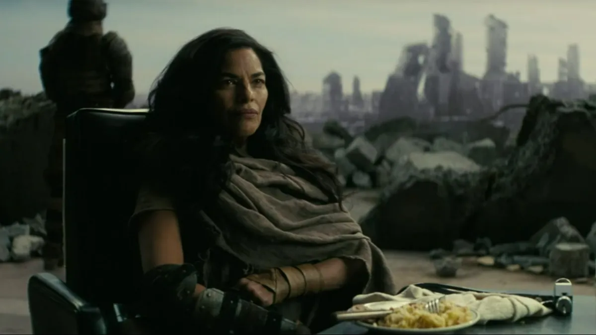 Moldaver in the Fallout TV series, a woman with long black hair sitting in a chair in front of an open wall.