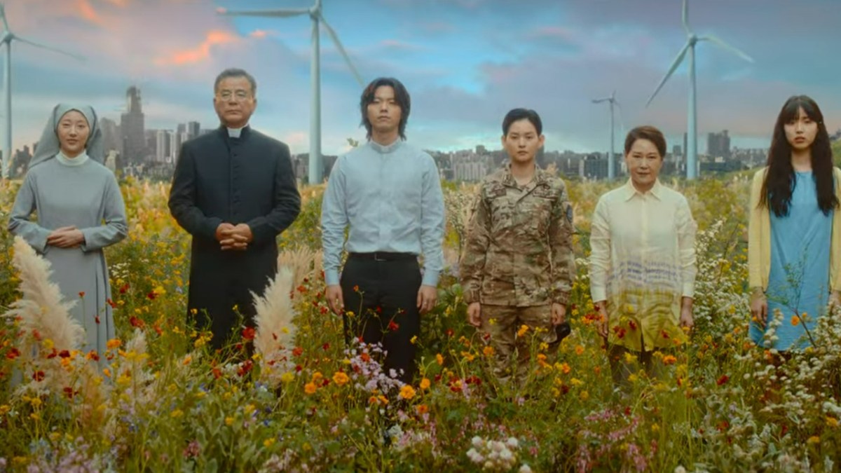 Several people, including a priest, standing in a field of flowers in Goodbye Earth.