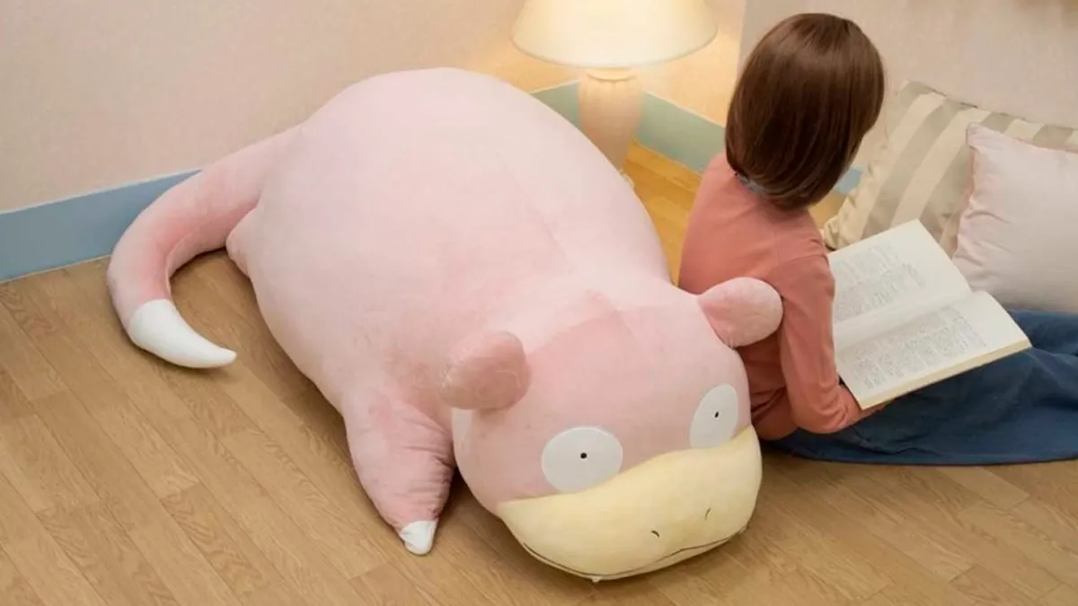 A giant plush Slowpoke with a child resting against it.
