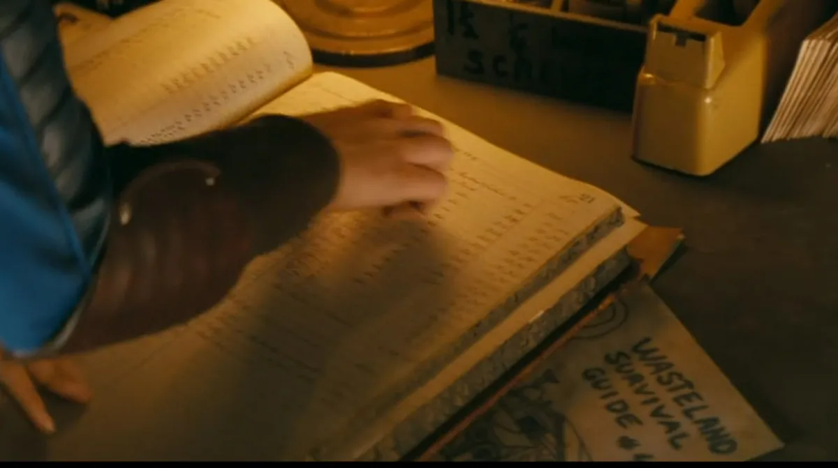 A woman reading a ledge in Fallout the series, with a Wasteland Survival Guide book beneath the big ledger. 