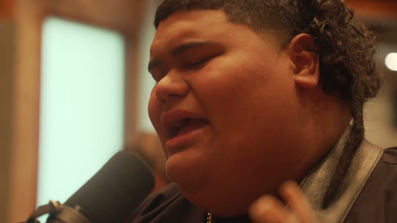 Singer Iam Tongi, singing into a microphone. This image is part of an article about all American Idol winners in order.