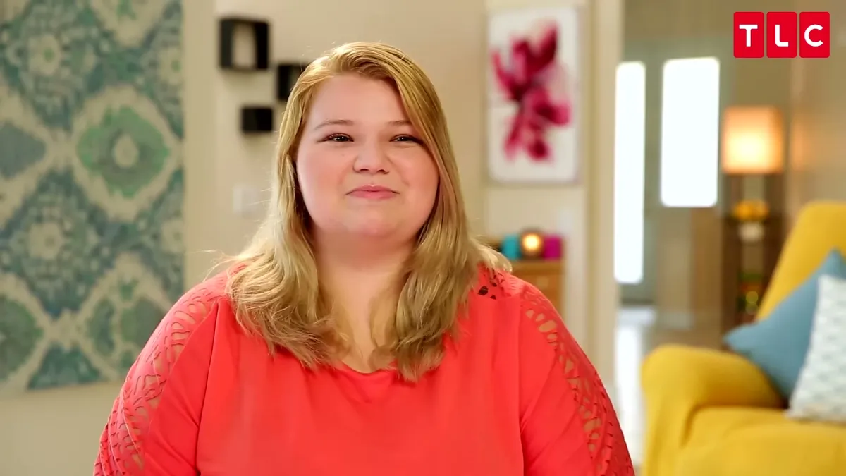 Nicole from 90 Day Fiance, a blonde woman in a red top sitting in a room.
