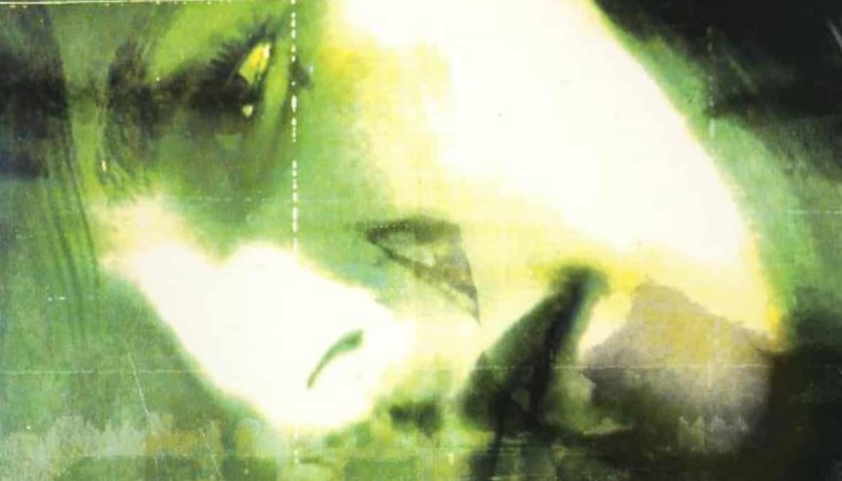 A haunting green-tinted image from Silent Hill featuring a blurred face and shadowy figure in the mist