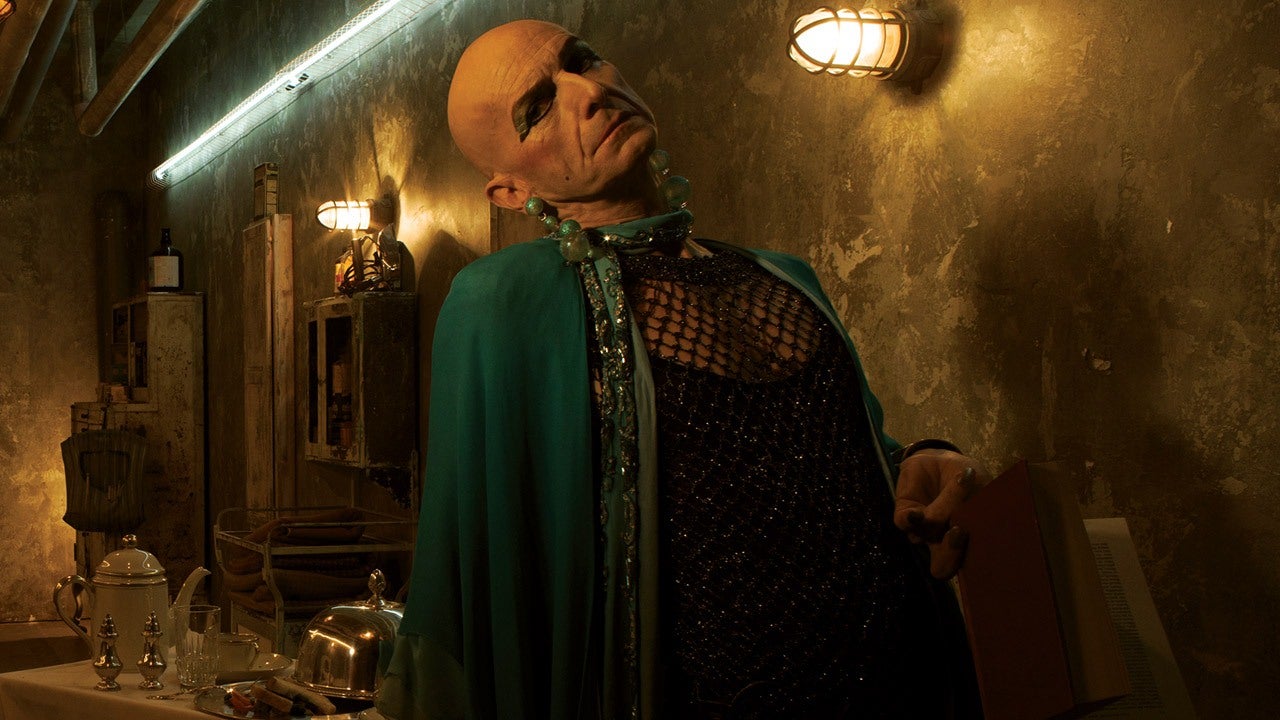 Liz leans back in a dingy room