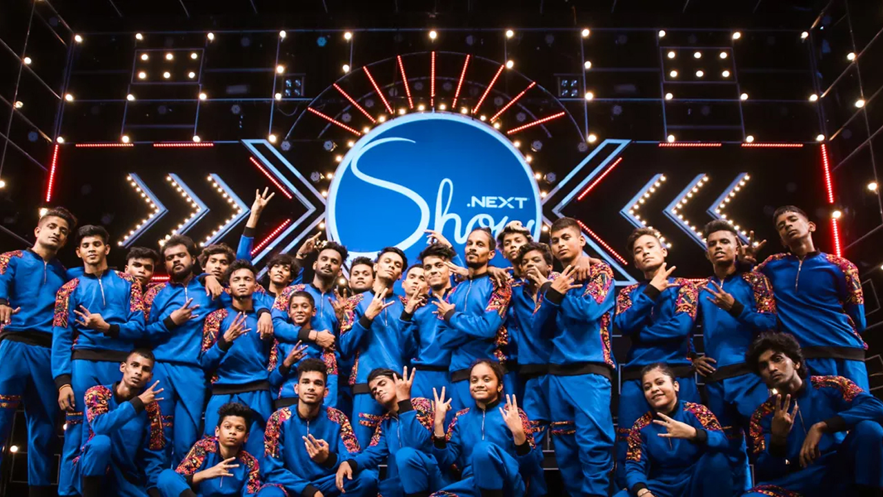 V. Unbeatable, a group of dancers in blue and orange jumpsuits.