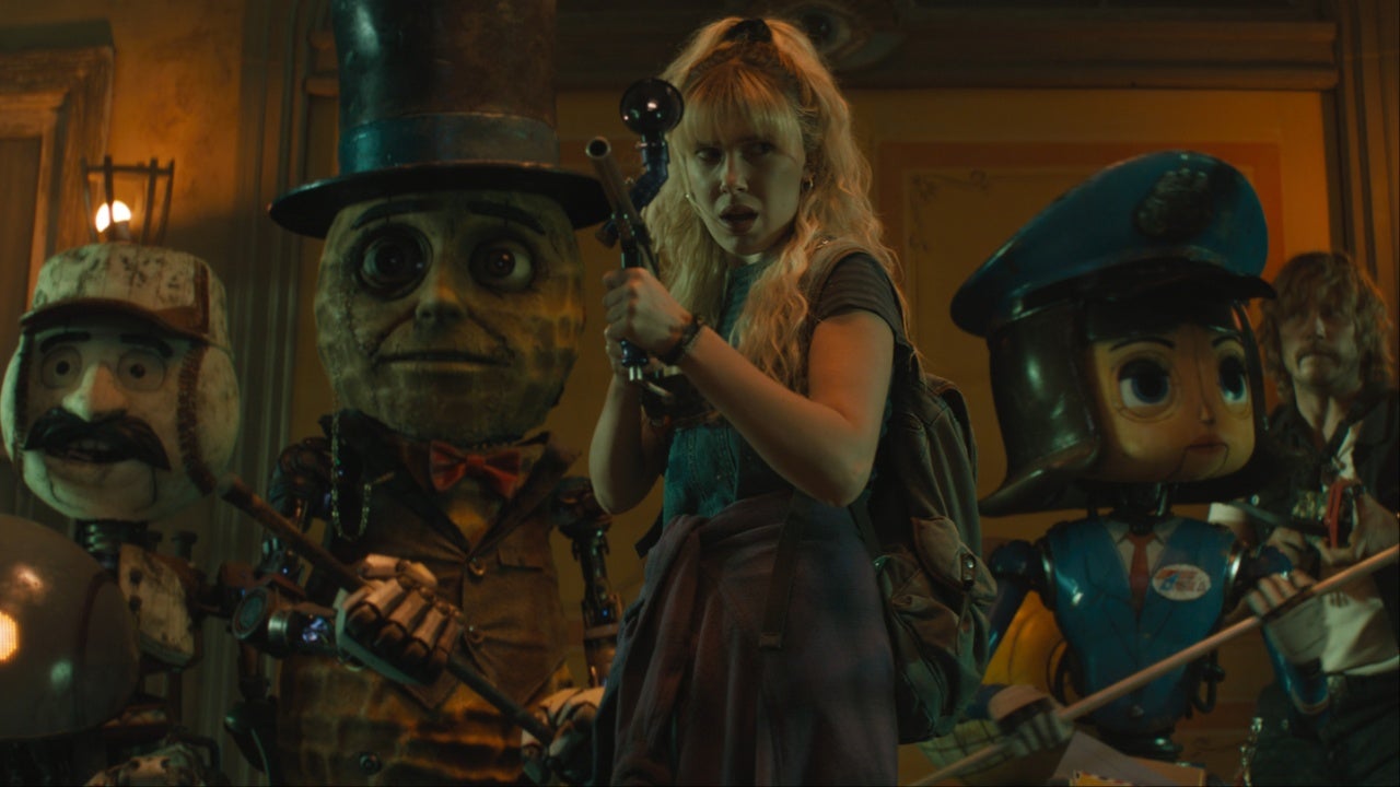 Michelle (Milly Bobby Brown) aims a gun while flanked by robots in The Electric State