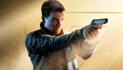 Young man aiming a handgun against a golden background — promo art for 007 First Light game.