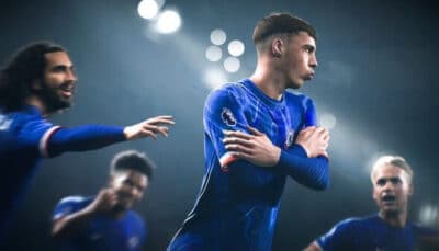 A soccer player in a blue jersey celebrates by folding his arms while teammates in the background express joy on a brightly lit field