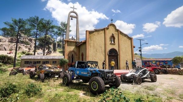 Four off-road vehicles parked in front of a chapel.