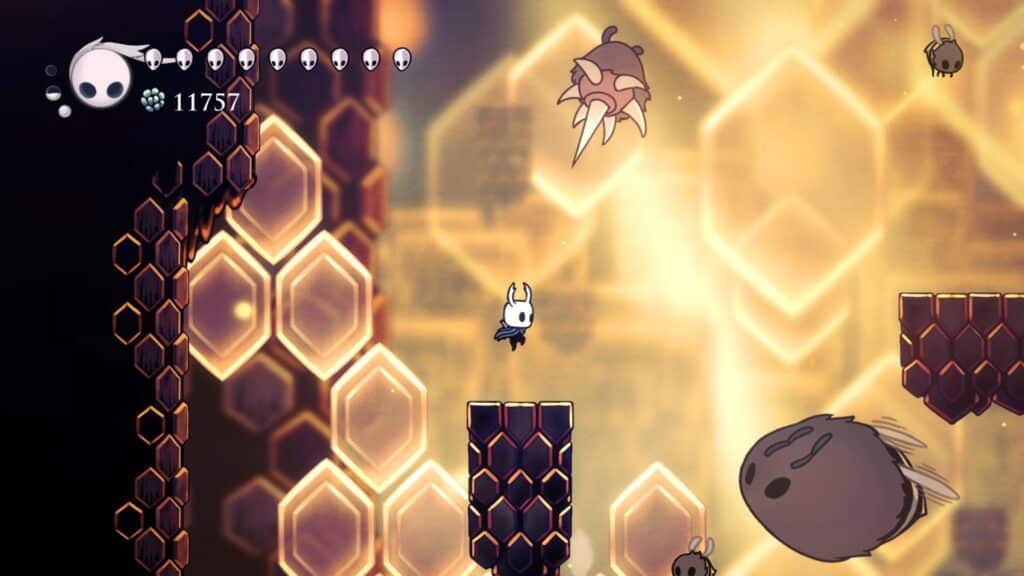 Screenshot from Hollow Knight showing the Knight fighting bee-like enemies inside the Hive zone.