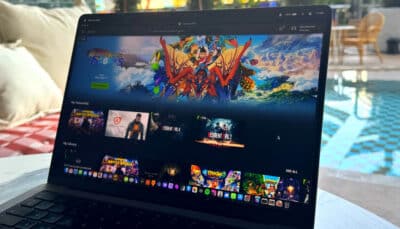 A laptop displays a game library interface while using Nvidia’s GeForce NOW by a poolside setting