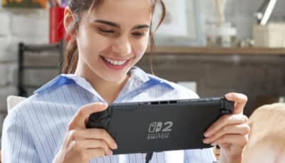A player smiles while holding the Nintendo Switch 2 in handheld mode at home