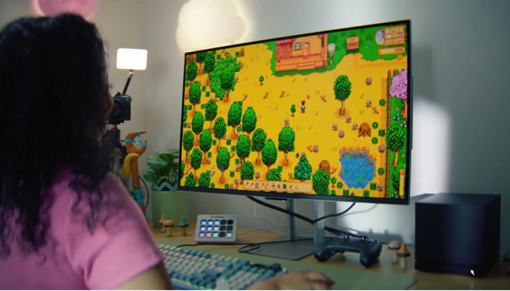 A player tends their growing farm in Stardew Valley on a large monitor.