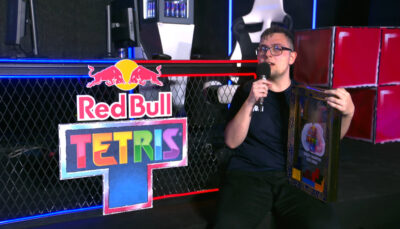 A winner holds the trophy while speaking on stage at The Tetris World Finals