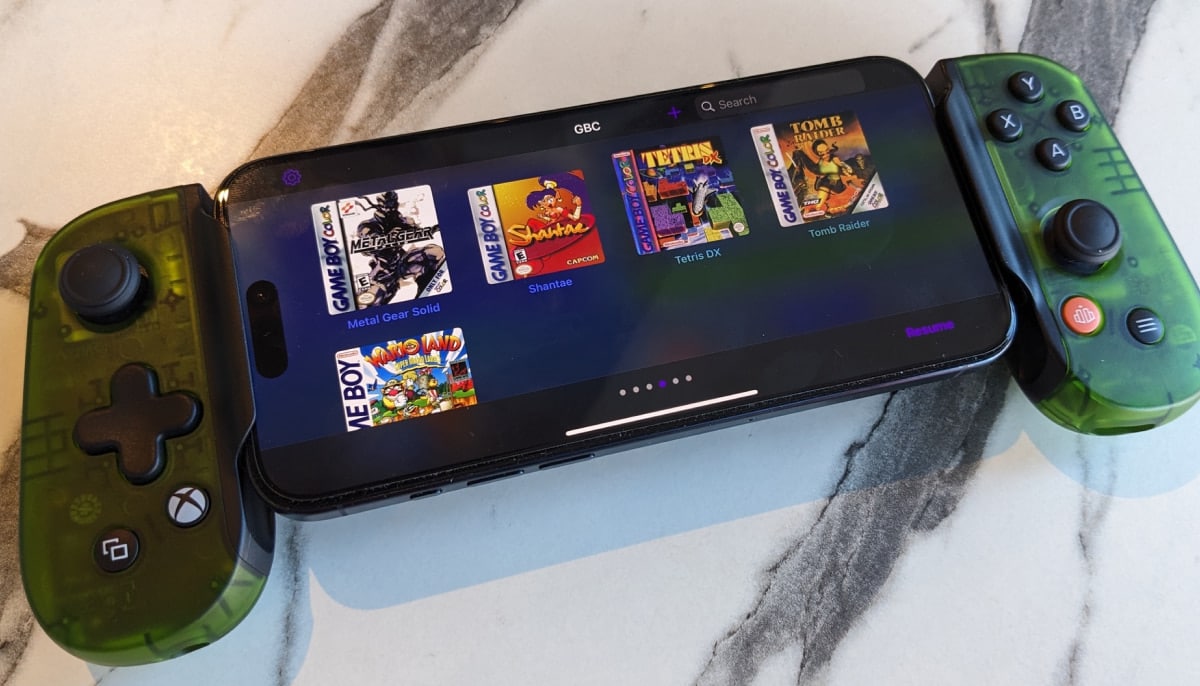 A smartphone fitted with gamepad controllers displays classic titles running through emulators