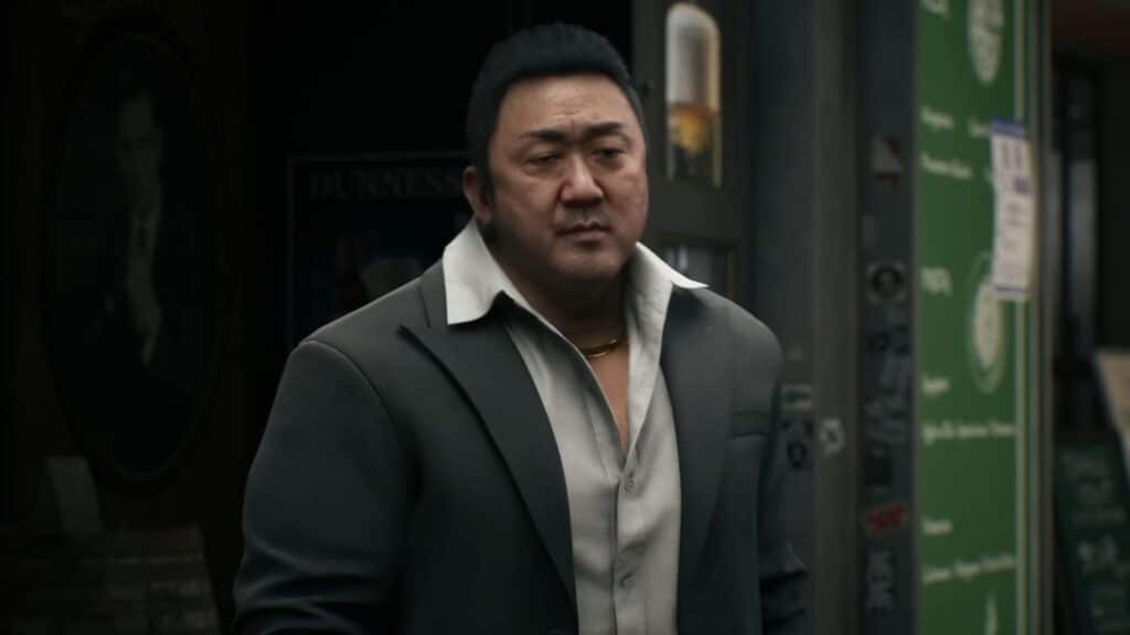 A suited character in Gang of Dragon stands outside a shop as the street lights glow around him