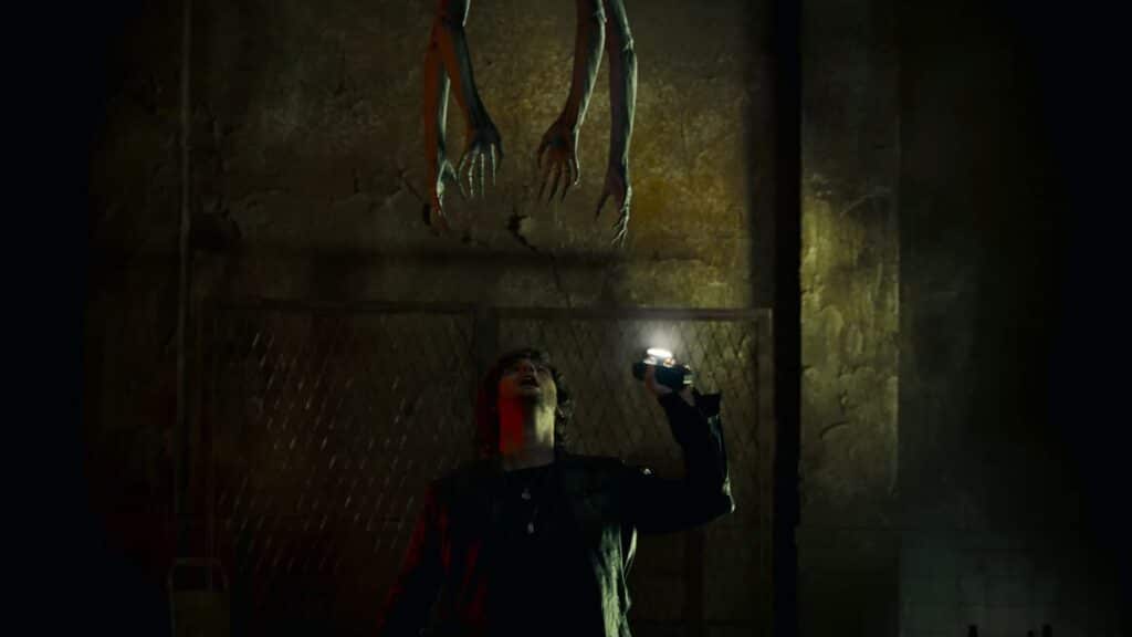 A character raises a flashlight while a twisted creature hangs from the ceiling in Silent Hill