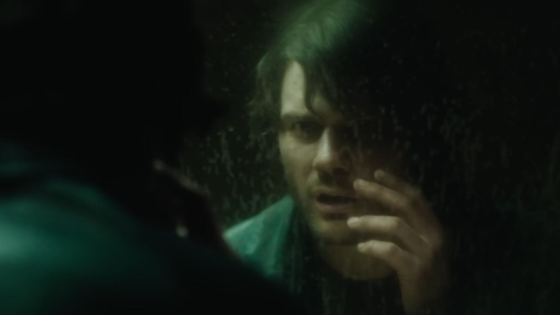 A man stares at his reflection through a dark foggy surface in Silent Hill