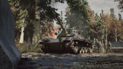 Picture of a tank from '83 in woodland camo, with troops flanking around it.