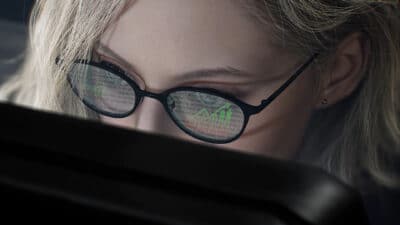Grace from Resident Evil Requiem looking at a PC monitor.